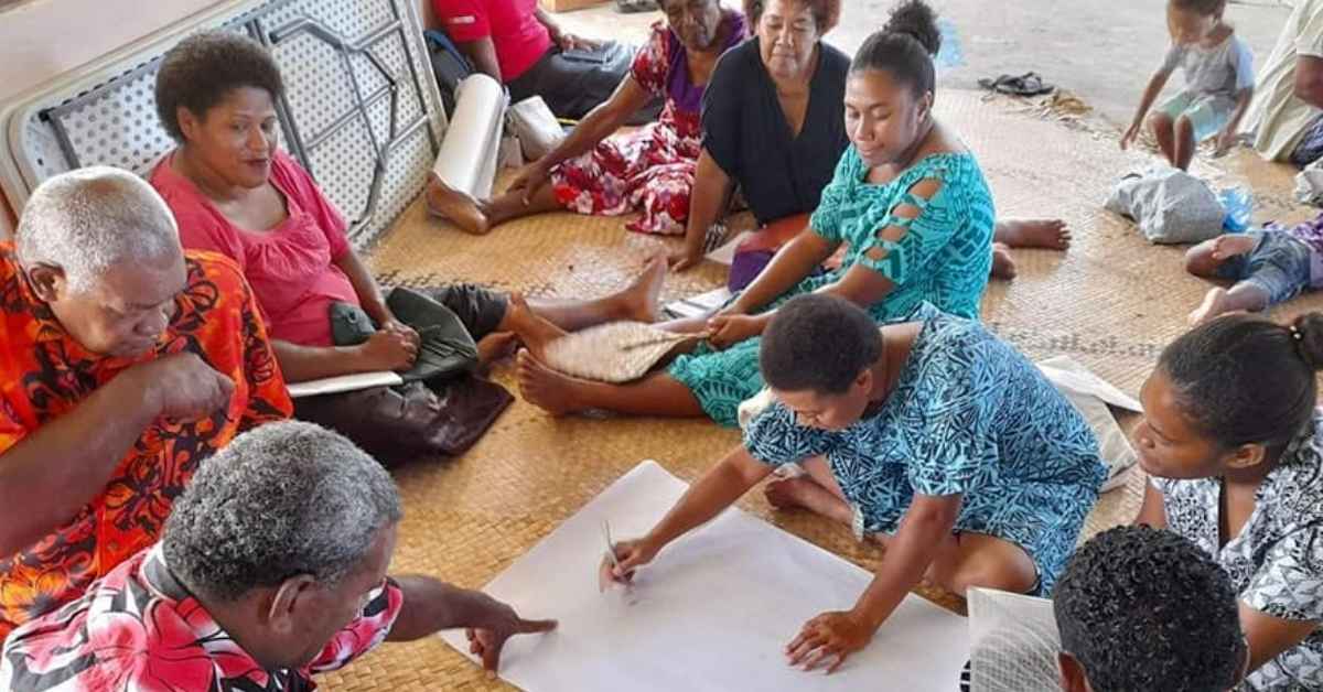 Community members participating in a disaster preparedness workshop, collaboratively planning strategies for Disaster Risk Reduction through community based approaches.